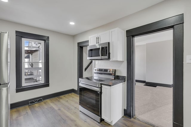 kitchen featuring dark countertops, white cabinets, visible vents, and stainless steel appliances