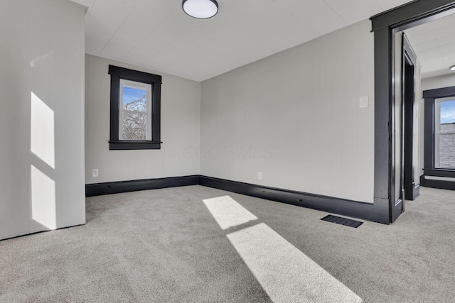 spare room featuring carpet, visible vents, and a healthy amount of sunlight