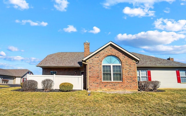 back of house with brick siding, a chimney, a yard, and a shingled roof