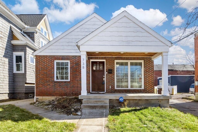 bungalow-style home featuring brick siding and covered porch