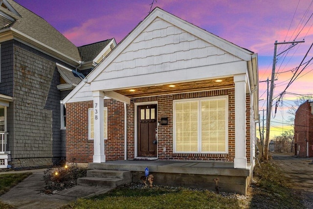 view of front facade with brick siding and a shingled roof