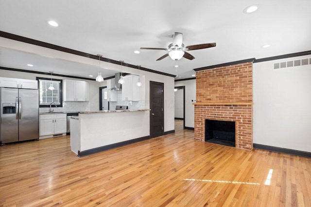 kitchen featuring visible vents, appliances with stainless steel finishes, a fireplace, white cabinetry, and a sink