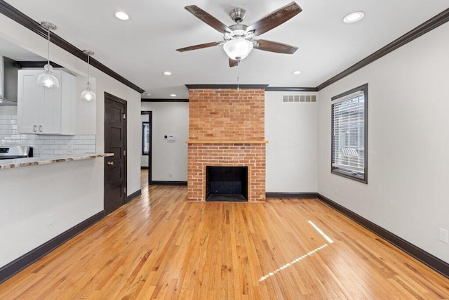 unfurnished living room with baseboards, visible vents, crown molding, a brick fireplace, and light wood-type flooring