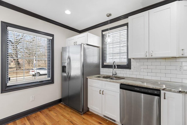 kitchen featuring a sink, light stone counters, tasteful backsplash, stainless steel appliances, and crown molding