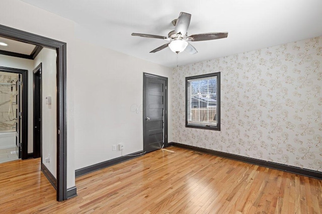 empty room with wallpapered walls, baseboards, light wood-type flooring, and ceiling fan