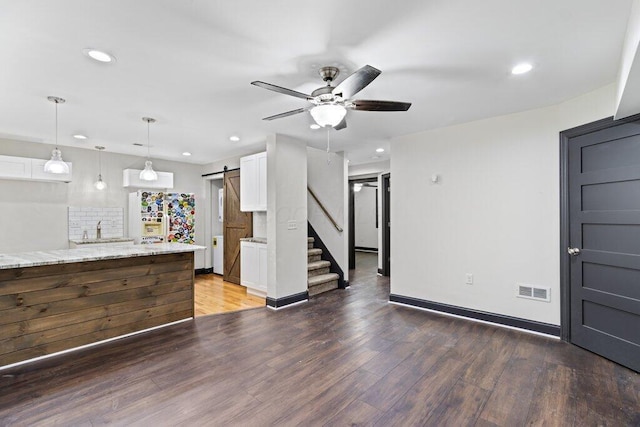 interior space with visible vents, recessed lighting, a barn door, and wood finished floors