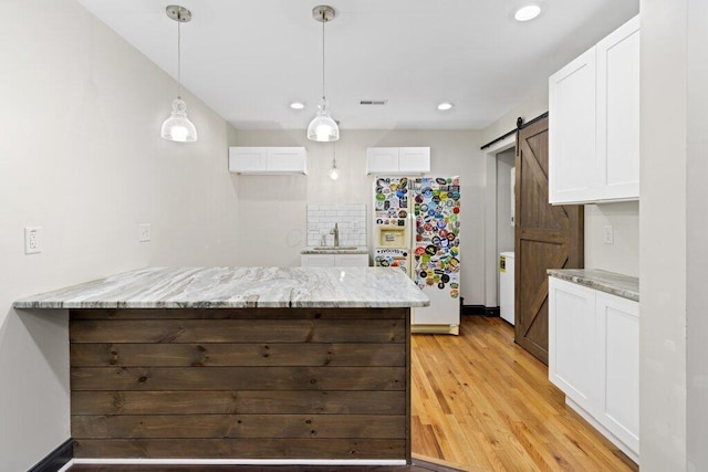 kitchen with white cabinetry, a barn door, a peninsula, and white fridge with ice dispenser