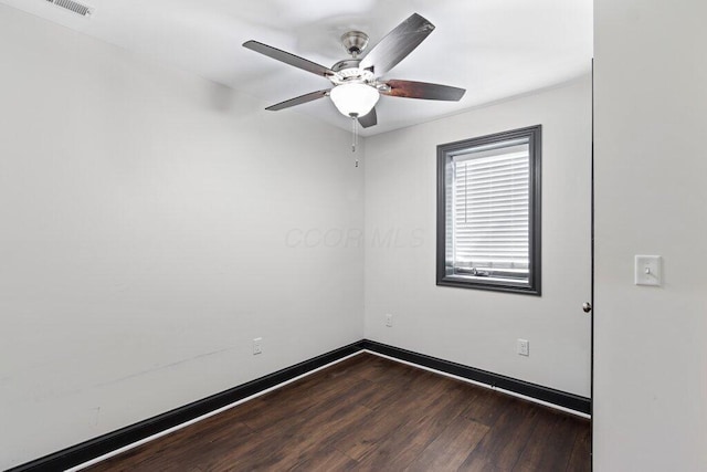 unfurnished room featuring baseboards, dark wood-type flooring, and a ceiling fan