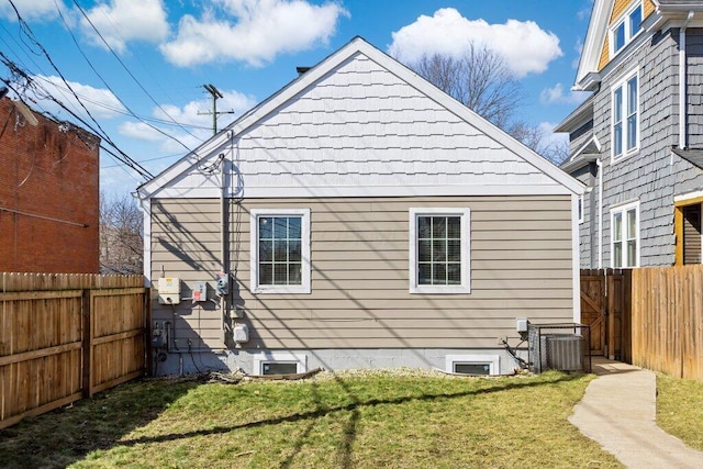 view of side of property with a lawn, central AC, and a fenced backyard