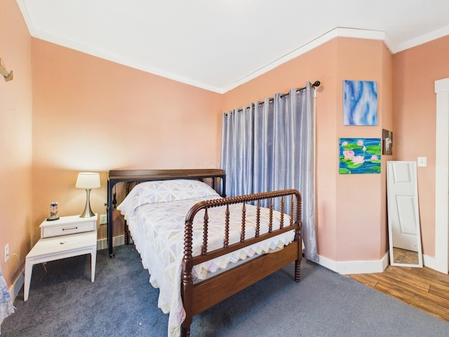 carpeted bedroom featuring crown molding, wood finished floors, and baseboards