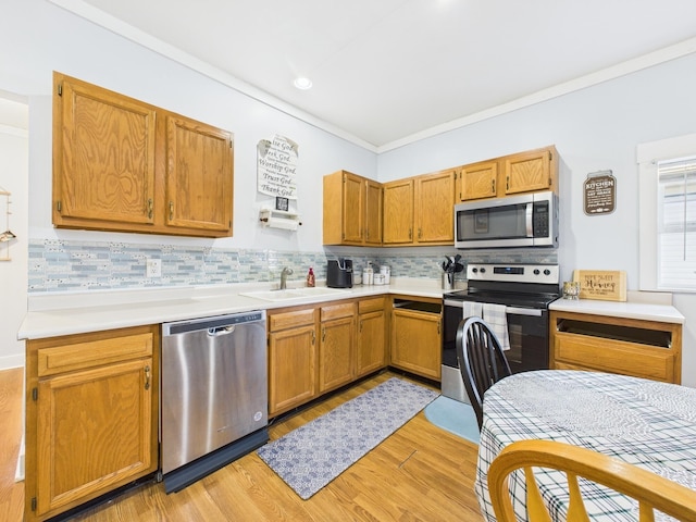 kitchen featuring light wood-style flooring, a sink, tasteful backsplash, stainless steel appliances, and light countertops