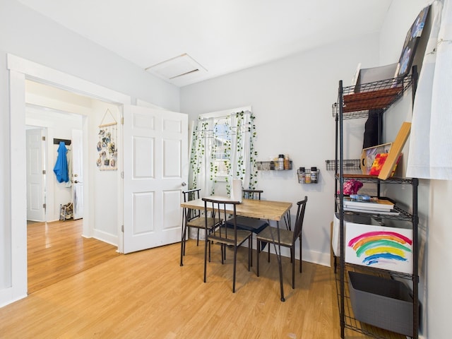 dining space with attic access, wood finished floors, and baseboards