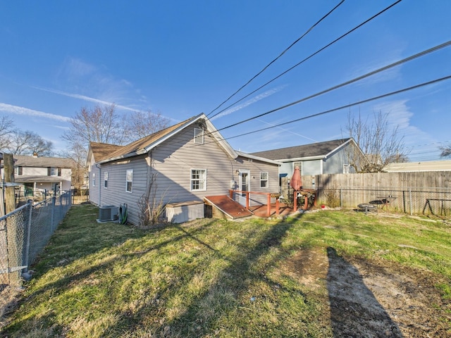 rear view of house with a wooden deck, a yard, central AC, and a fenced backyard