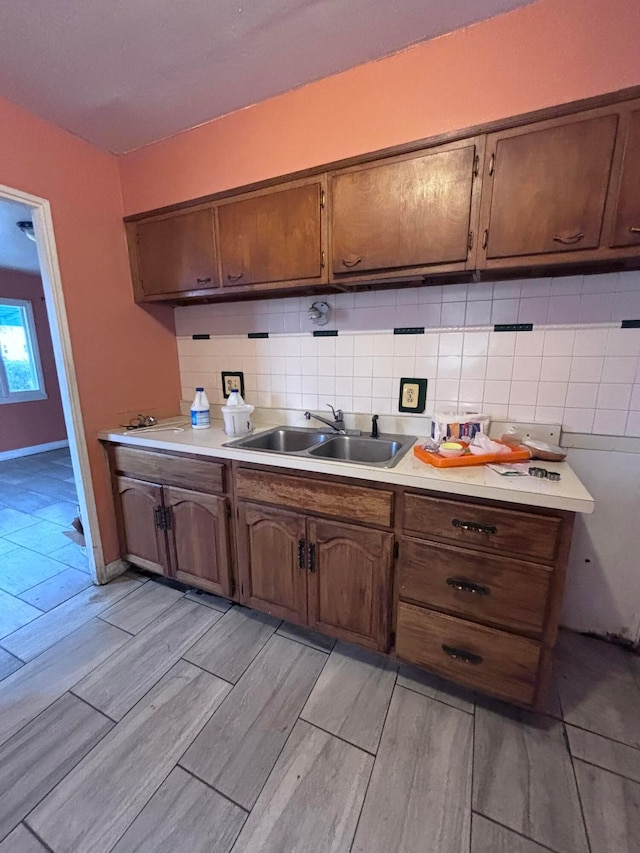 kitchen featuring a sink, light wood-style floors, backsplash, and light countertops