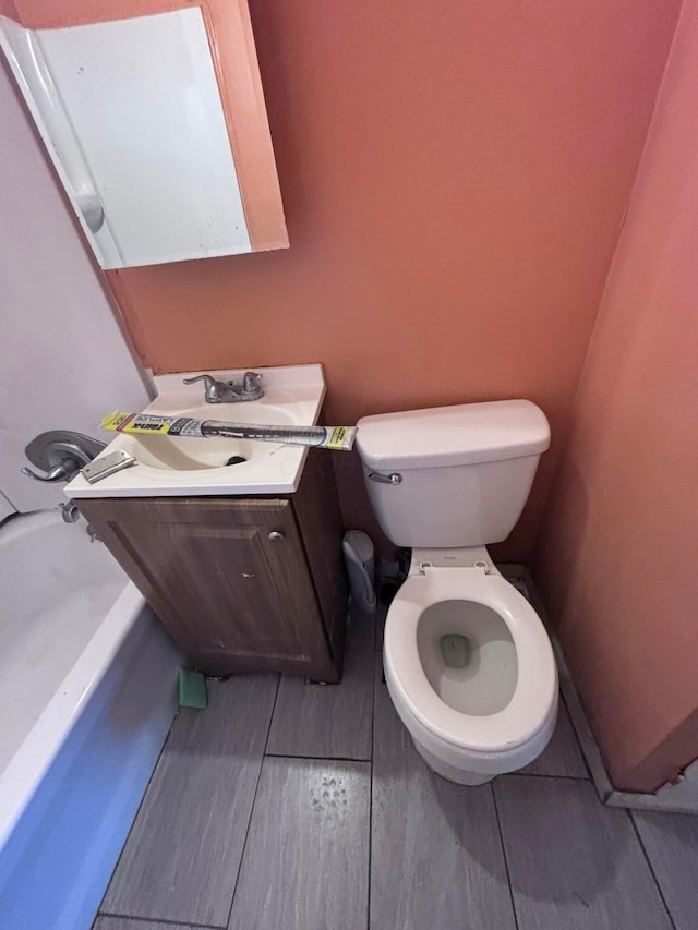 bathroom featuring vanity, toilet, and a bath