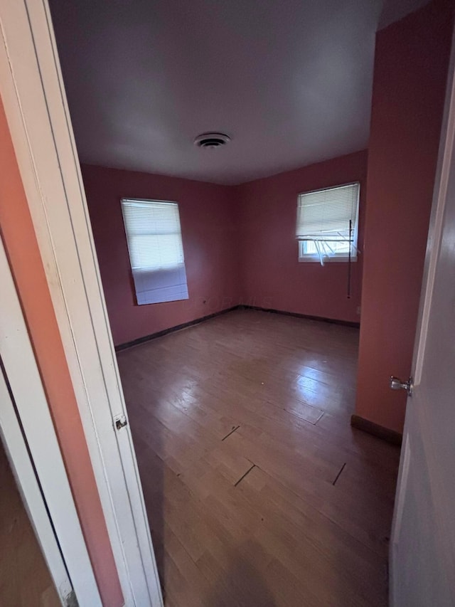 empty room featuring visible vents, baseboards, and wood finished floors