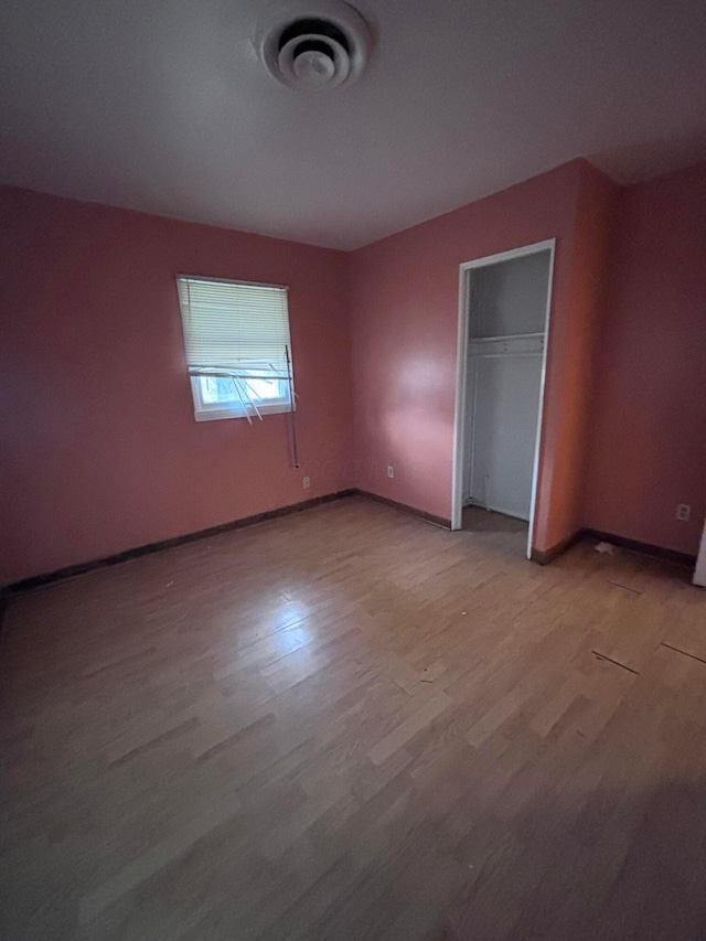 unfurnished bedroom featuring a closet, baseboards, visible vents, and light wood finished floors