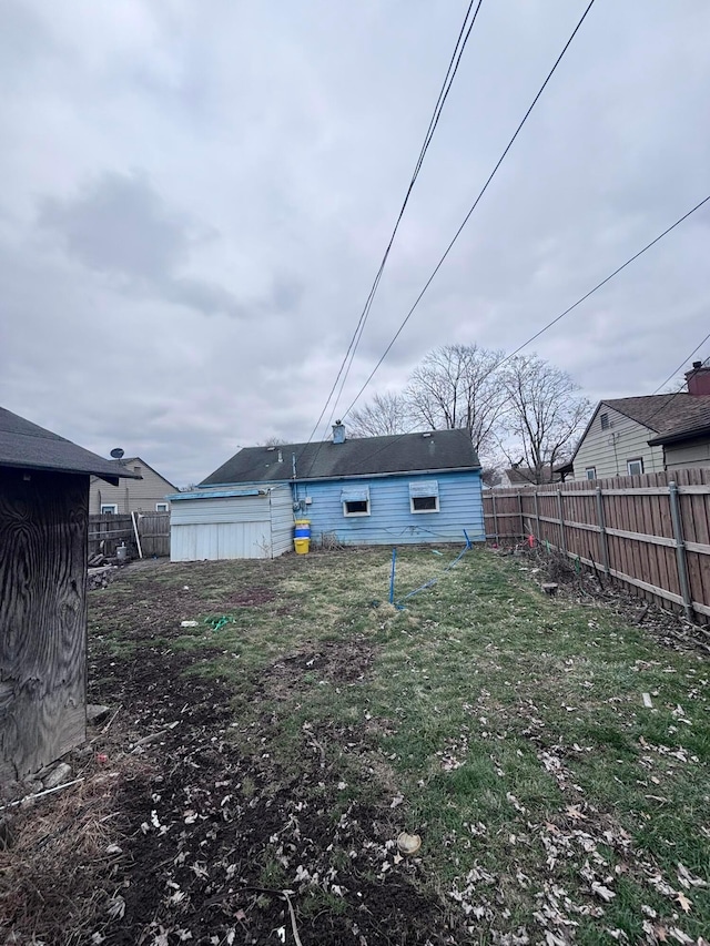 back of house with an outbuilding, a lawn, and a fenced backyard