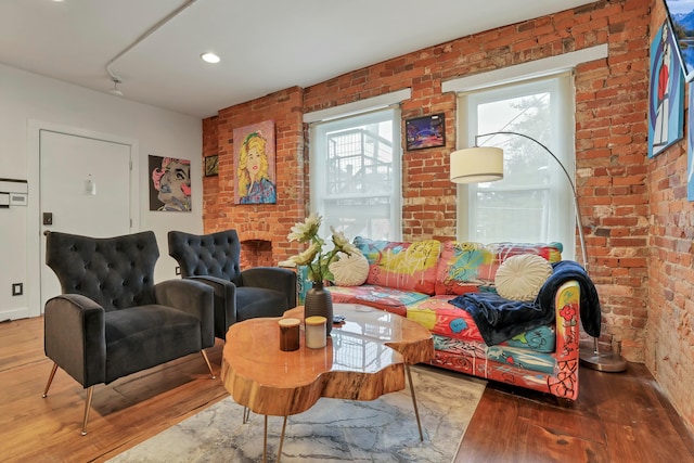 living room with wood finished floors and brick wall