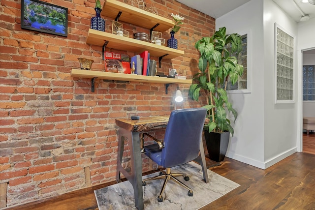 office space with brick wall, baseboards, and wood finished floors