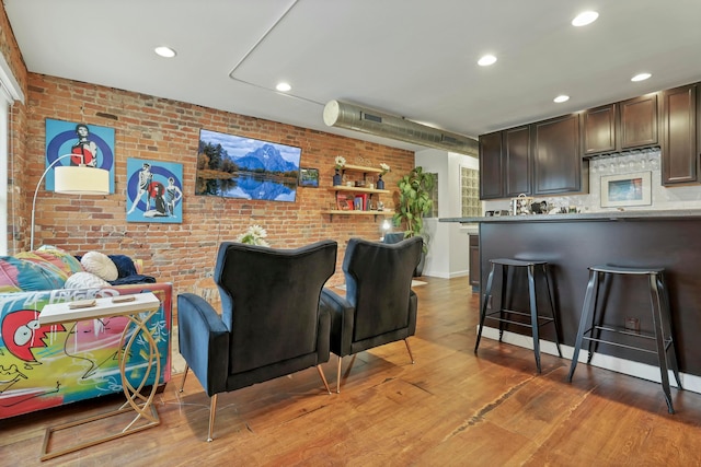 home theater room featuring light wood finished floors, recessed lighting, and brick wall