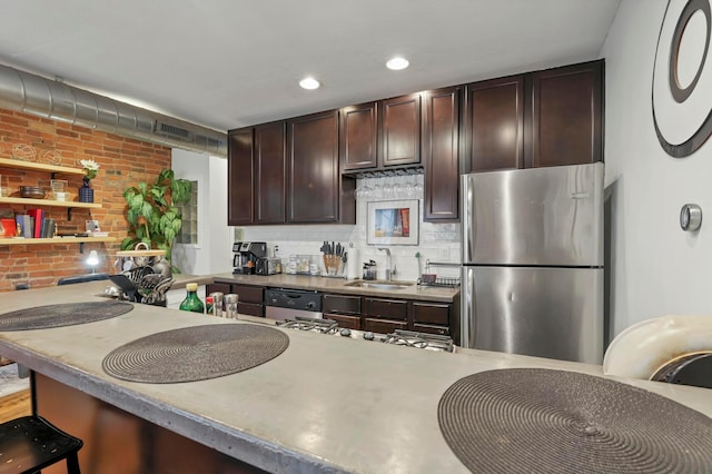 kitchen with a sink, backsplash, appliances with stainless steel finishes, brick wall, and dark brown cabinets