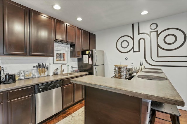 kitchen with a sink, tasteful backsplash, appliances with stainless steel finishes, and dark brown cabinets