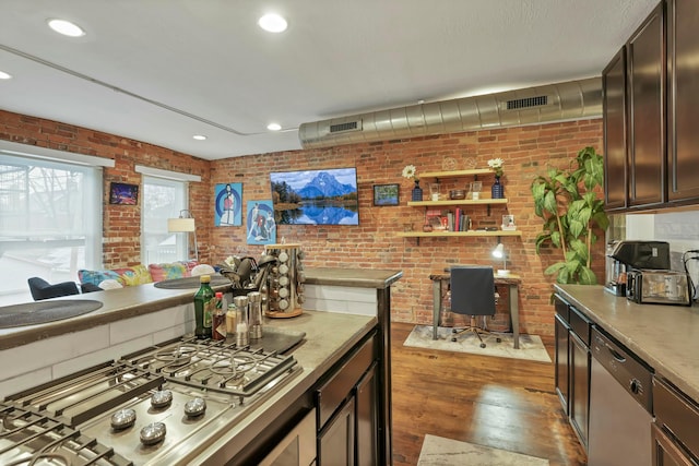 kitchen with visible vents, brick wall, stainless steel appliances, and wood finished floors