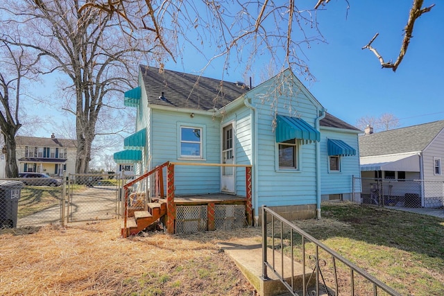 rear view of property with a gate, fence, and roof with shingles