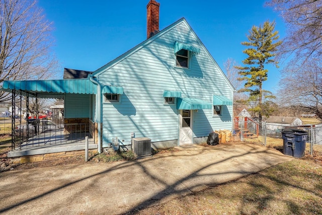 rear view of property with fence, central AC, a chimney, driveway, and a gate