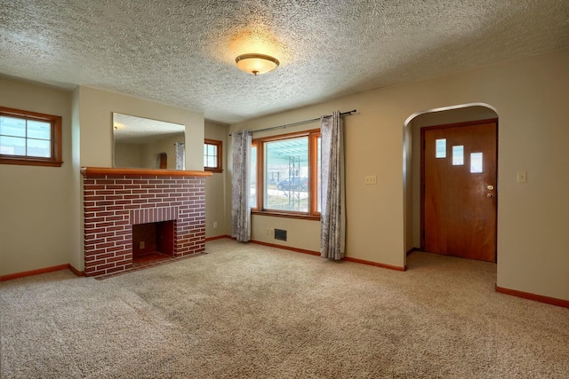 unfurnished living room featuring a wealth of natural light, carpet flooring, a fireplace, and baseboards