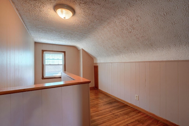 additional living space with lofted ceiling, wood finished floors, and a textured ceiling