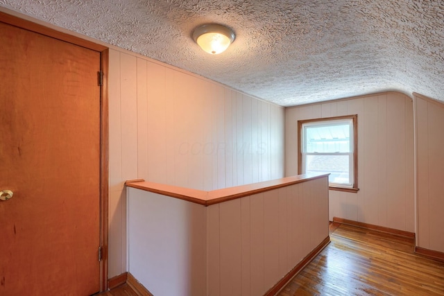 hall with wood finished floors and a textured ceiling