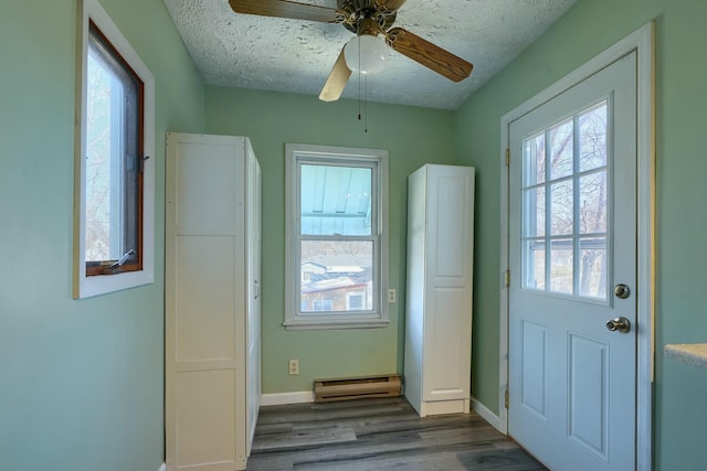 doorway featuring baseboards, baseboard heating, dark wood finished floors, and a textured ceiling