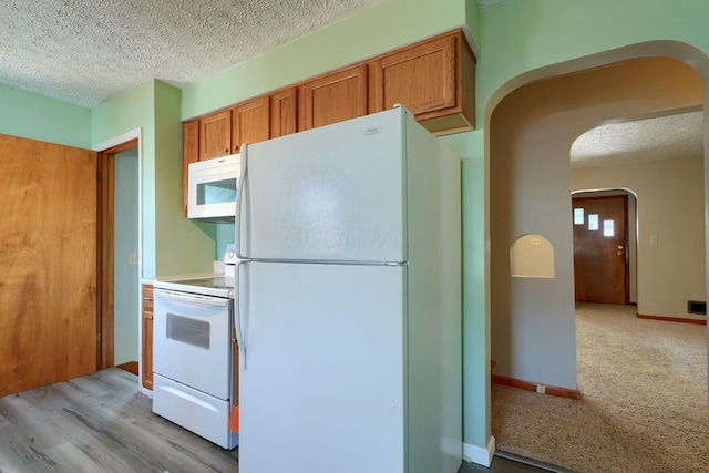 kitchen with white appliances, brown cabinets, arched walkways, and a textured ceiling