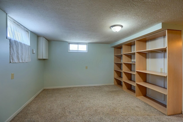 basement featuring light colored carpet, a textured ceiling, and baseboards