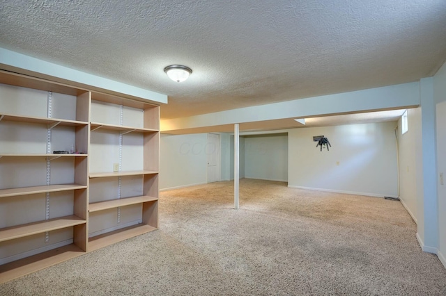 finished basement with a textured ceiling, baseboards, and carpet