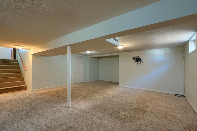 finished basement featuring carpet flooring, baseboards, a textured ceiling, and stairs