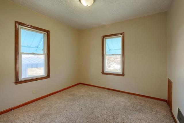 spare room featuring baseboards, light colored carpet, and a textured ceiling