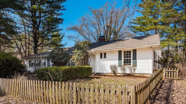 view of home's exterior with fence private yard, a chimney, and a shingled roof