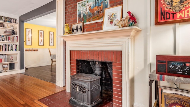 room details featuring built in features, a wood stove, baseboards, and wood finished floors