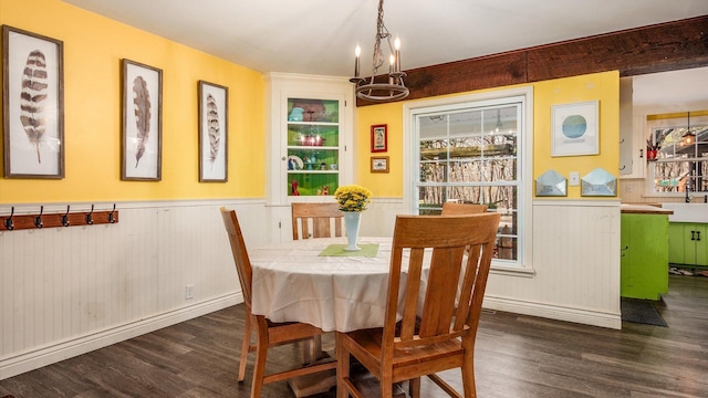 dining area featuring an inviting chandelier, dark wood-style floors, and a wainscoted wall