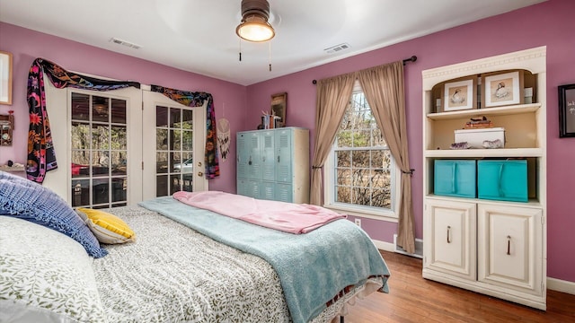 bedroom with visible vents, baseboards, wood finished floors, and access to outside