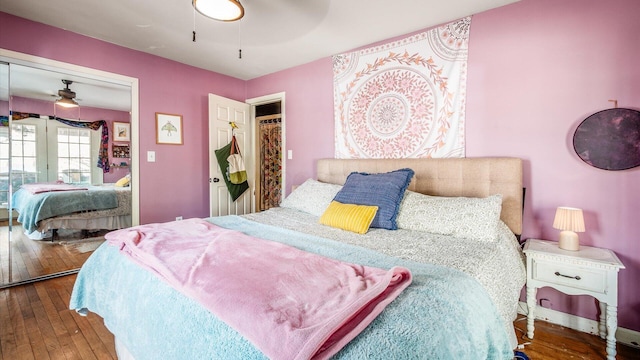 bedroom with a closet, wood-type flooring, and a ceiling fan