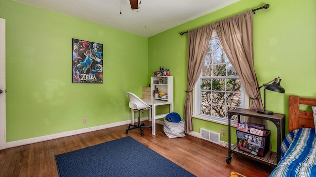 home office with a ceiling fan, wood finished floors, visible vents, and baseboards