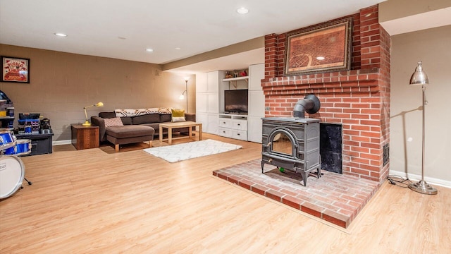 living room featuring recessed lighting, baseboards, a wood stove, and light wood-style floors