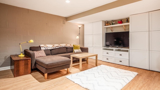 living area with light wood-style floors and concrete block wall