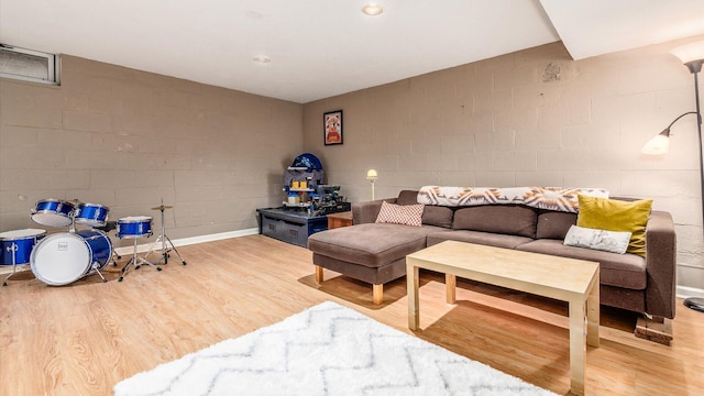 living area with concrete block wall and wood finished floors