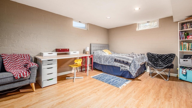 bedroom featuring recessed lighting, wood finished floors, and concrete block wall