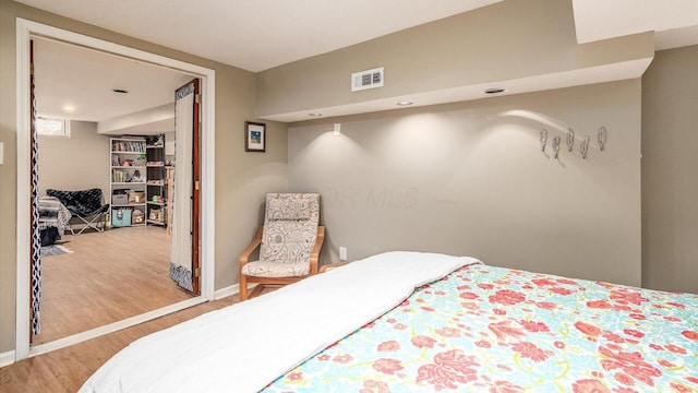 bedroom with visible vents, baseboards, and wood finished floors